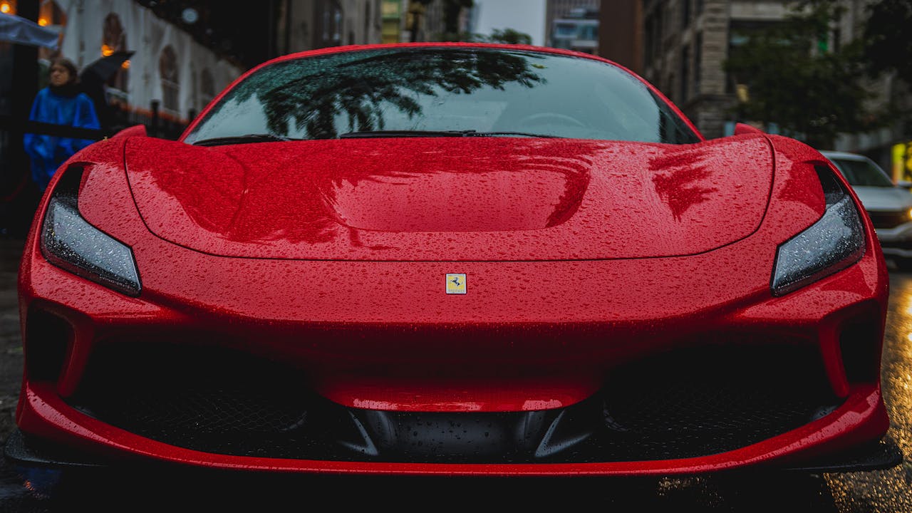 Front view of a vibrant red Ferrari parked on a rainy city street.