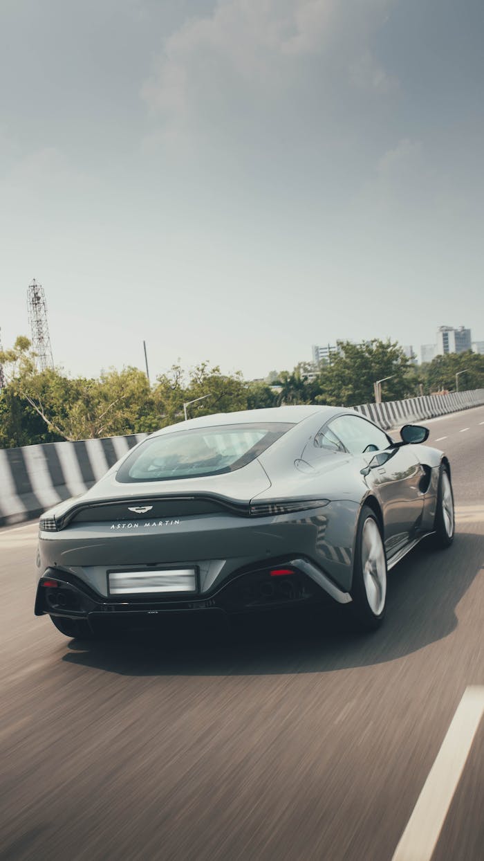 A sleek luxury sports car cruises on a sunny New Delhi highway, showcasing speed and style.